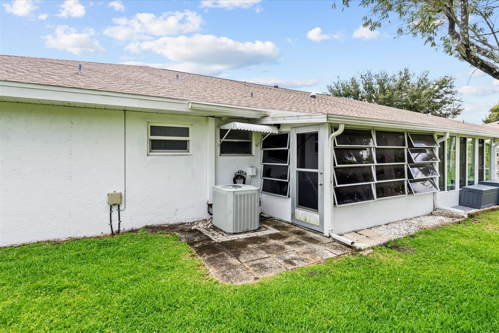 The exterior of a white house features a concrete patio, an air conditioning unit, and a sunroom — 127 LAKES END DRIVE UNIT C, FORT PIERCE, FL