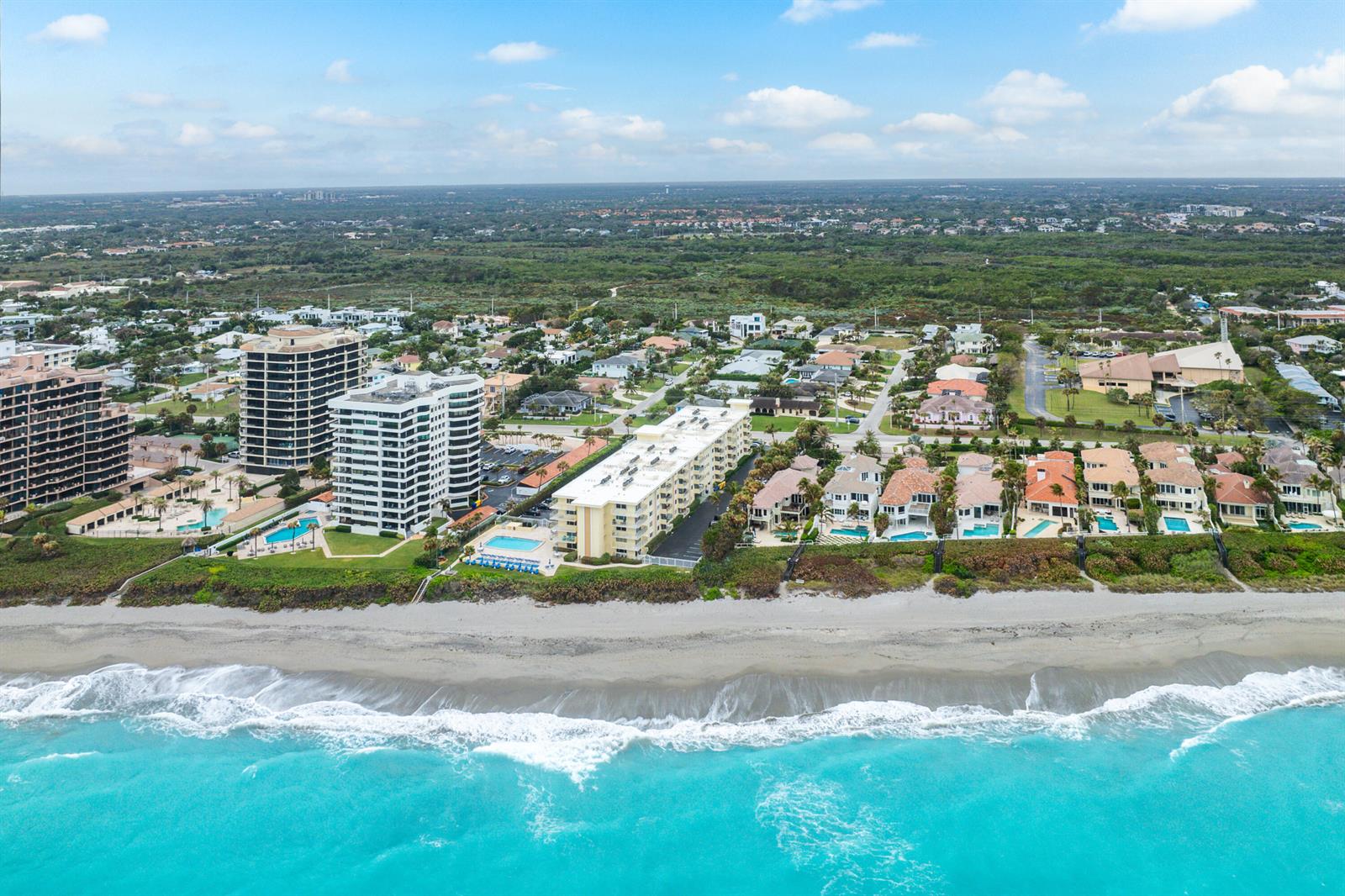 An aerial view shows beachfront condominiums and houses along a sandy coastline — 630 Ocean Drive # 410, Juno Beach FL 33408, JUNO BEACH, FL