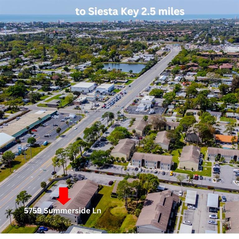 An aerial view shows a residential apartment building with a red arrow pointing to it — 5797 SUMMER SIDE LANE UNIT 7A, SARASOTA, FL