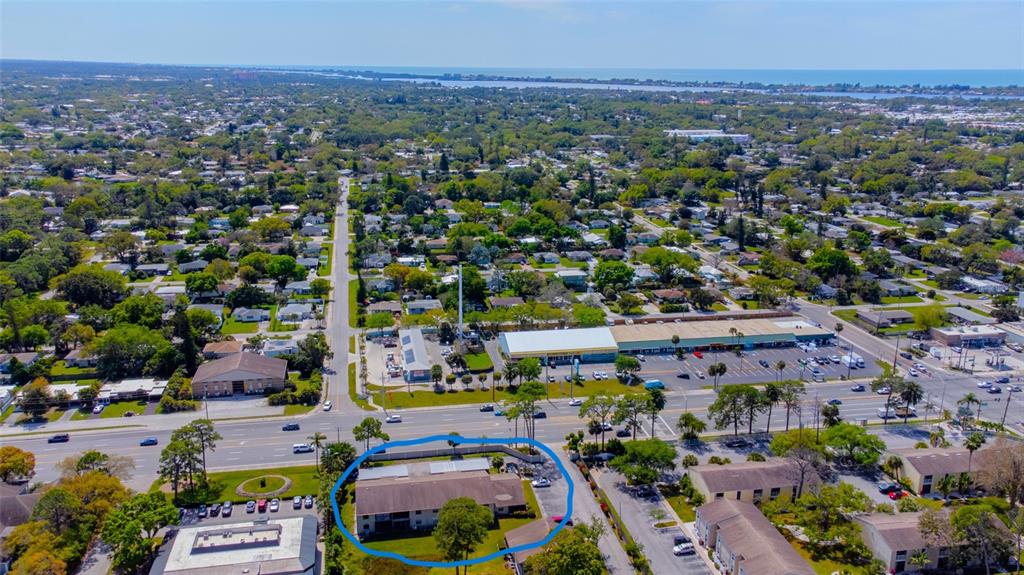 An aerial view shows a single-story apartment building circled in blue near a busy intersection — 5797 SUMMER SIDE LANE UNIT 7A, SARASOTA, FL