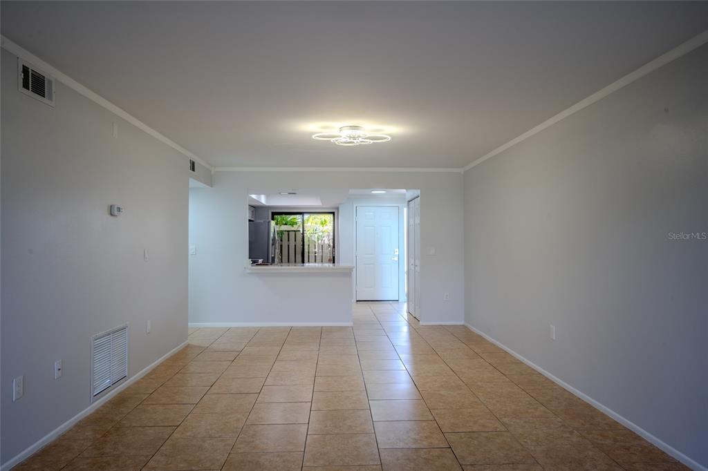 An open-concept living area features light gray walls, tan tile flooring, and a kitchen pass-through — 5797 SUMMER SIDE LANE UNIT 7A, SARASOTA, FL
