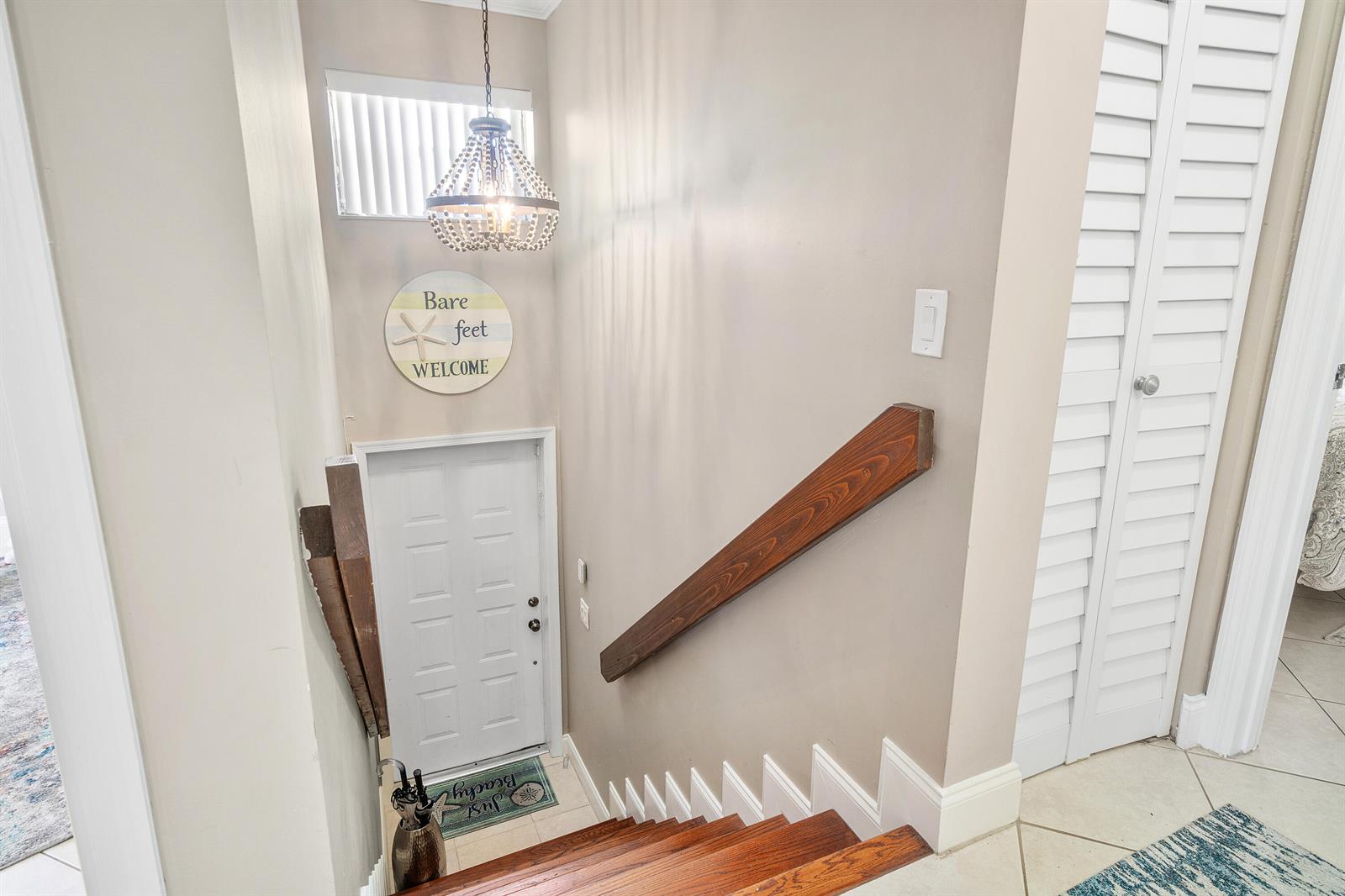A wooden staircase leads down to a white door with a beach-themed sign above — 312 Liberty Court, Deerfield Beach FL 33442, DEERFIELD BEACH, FL