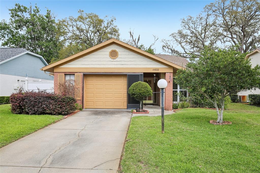 A single-story brick and siding house features a one-car garage and a front lawn — 11622 COCOWOOD DRIVE, NEW PORT RICHEY, FL