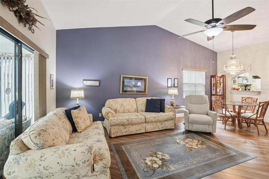 A living room features floral sofas, a blue accent wall, and a dining area nearby — 11622 COCOWOOD DRIVE, NEW PORT RICHEY, FL