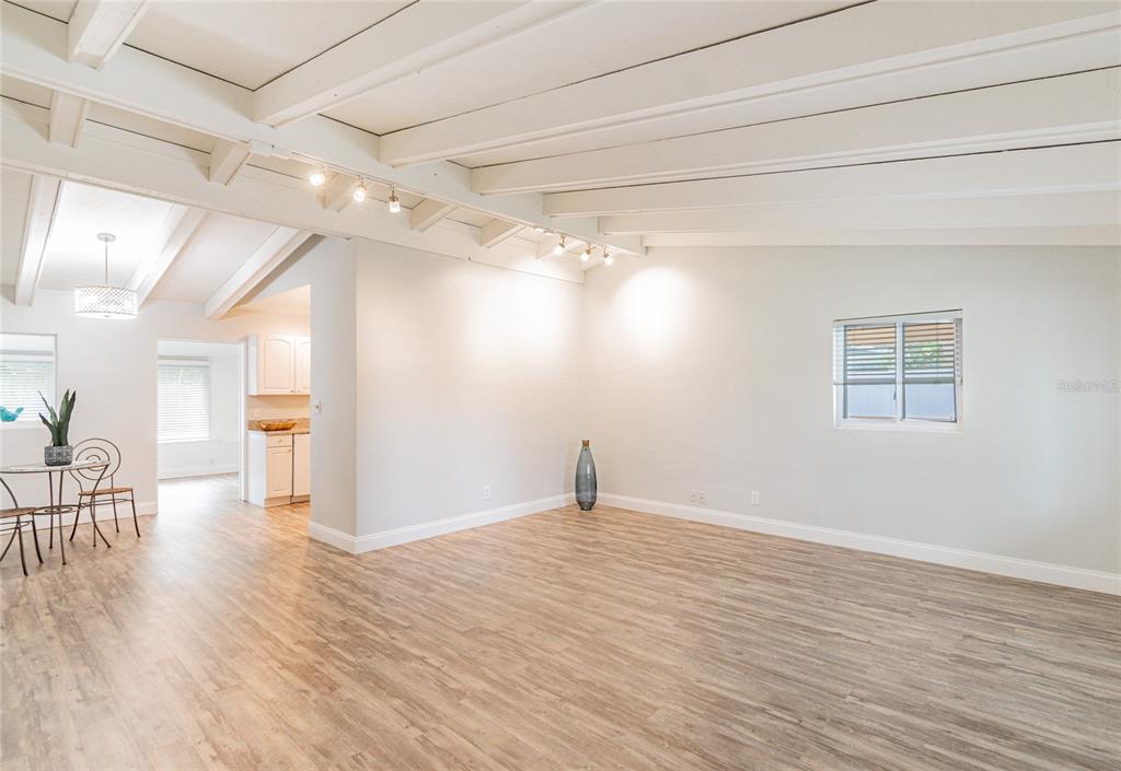 A bright, open-concept living area features white vaulted ceilings, track lighting, and wood-look flooring — 2010 SUMMERFIELD ROAD, WINTER PARK, FL