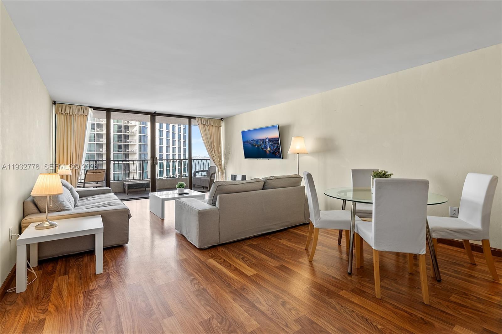 A dining area with a glass table and four chairs sits adjacent to a kitchen counter — 555 NE 15th St # 14G, Miami FL 33132, MIAMI, FL