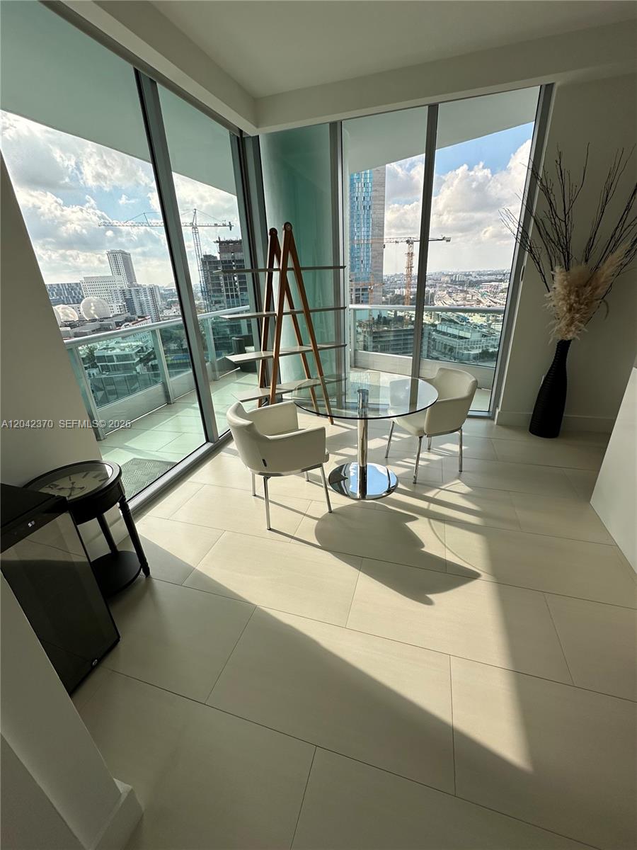A dining area with a glass table and two chairs sits before floor-to-ceiling windows — 900 Biscayne Blvd # 2312, Miami FL 33132, MIAMI, FL
