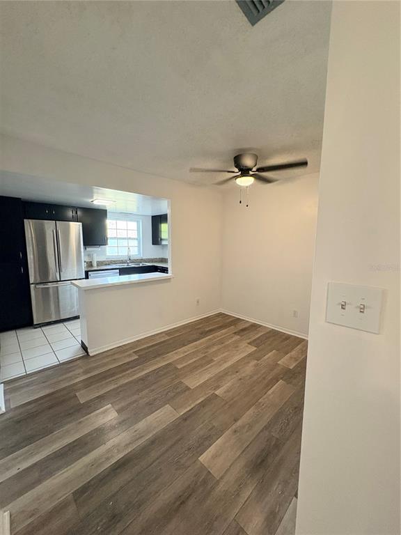 A dining area with wood-look flooring opens to a kitchen featuring stainless steel appliances — 1131 84TH AVENUE N UNIT D, ST PETERSBURG, FL