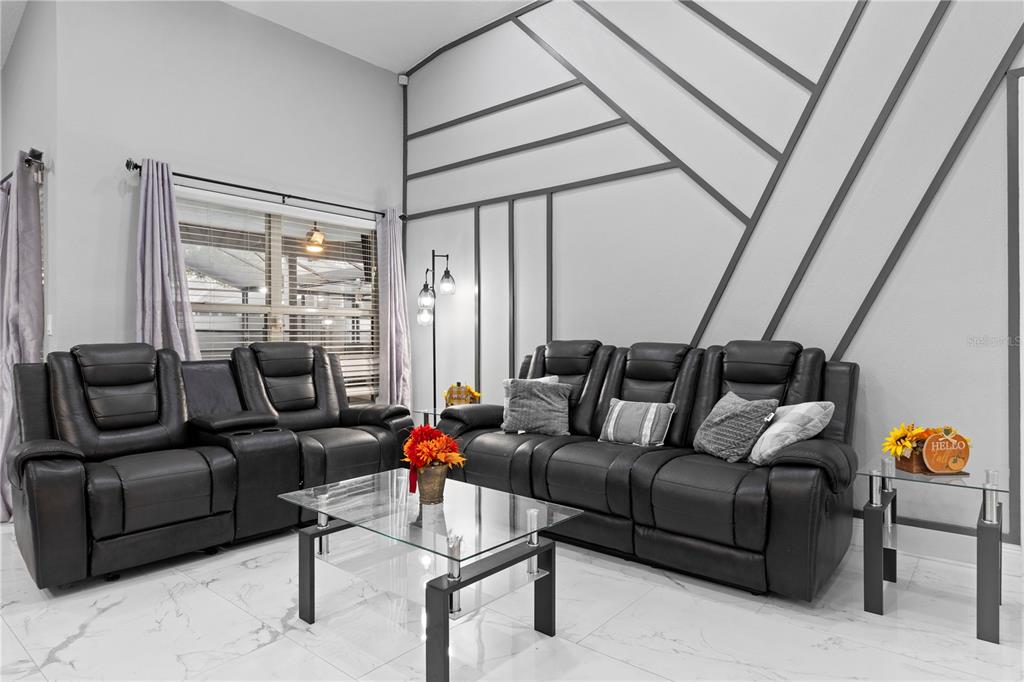 A living room features black leather reclining sofas, a glass coffee table, and geometric wall molding — 416 BECKY STREET, ORLANDO, FL