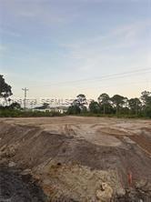 A vacant, cleared lot of land with dirt ground and trees in the background — 946 columbus blvd, Lehigh Acres FL 33974, LEHIGH ACRES, FL
