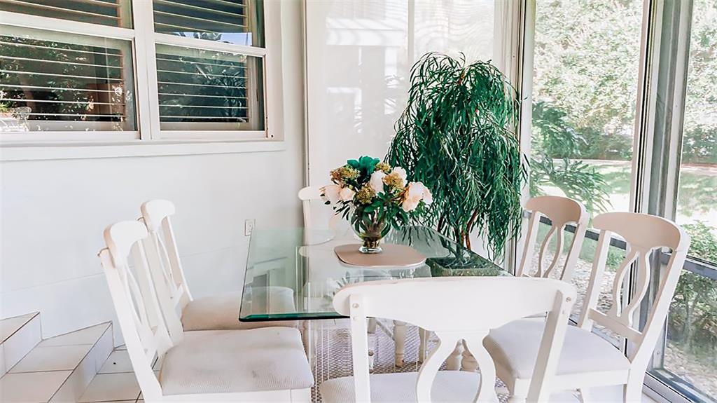 A sunroom features a glass-topped dining table with white chairs and a large potted plant — 1269 SIESTA BAYSIDE DRIVE UNIT 1269-C, SARASOTA, FL