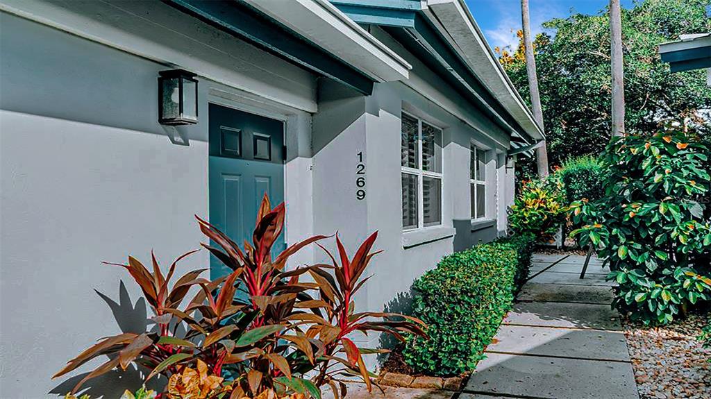 The exterior of a light gray house features a blue door and a paved walkway — 1269 SIESTA BAYSIDE DRIVE UNIT 1269-C, SARASOTA, FL