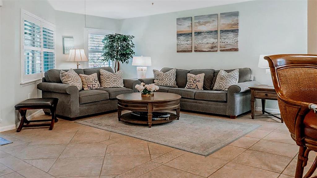 A living room features two gray sofas, a round wooden coffee table, and tile flooring — 1269 SIESTA BAYSIDE DRIVE UNIT 1269-C, SARASOTA, FL