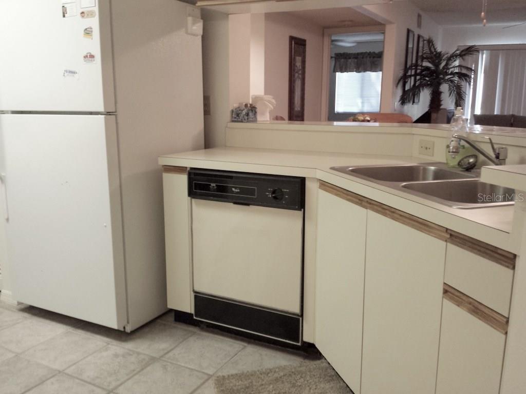 A kitchen features white cabinets, a white refrigerator, a black dishwasher, and a double sink — 4449 46TH AVENUE W UNIT 4449, BRADENTON, FL