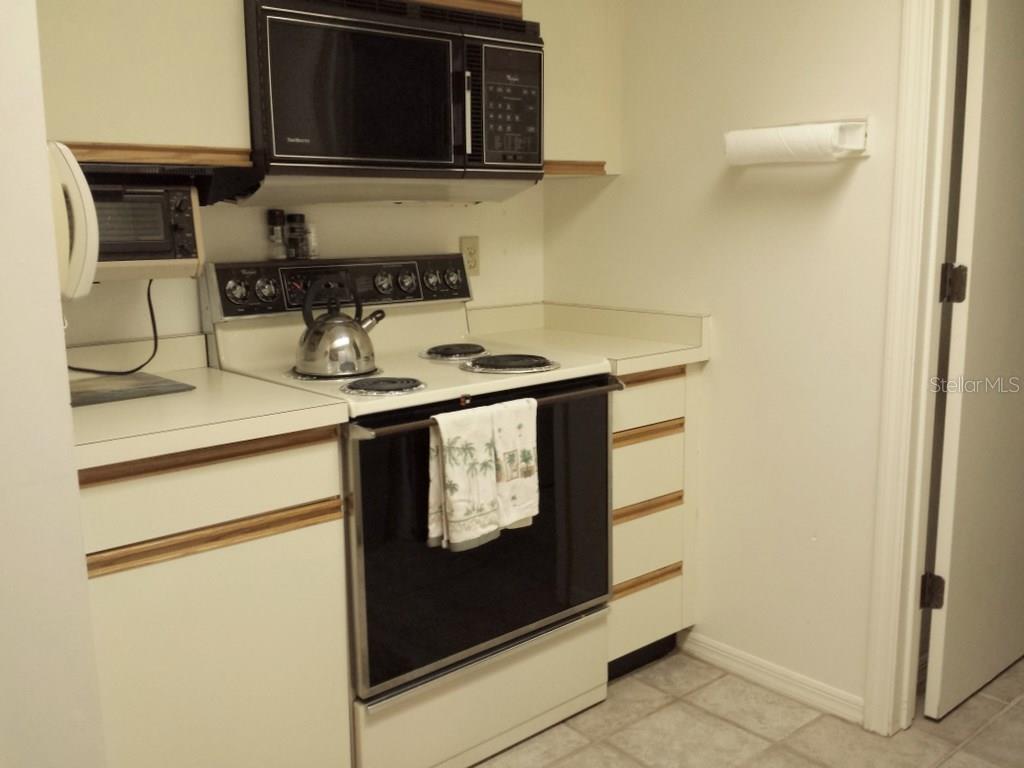 A kitchen features white cabinets, a black electric stove, and a mounted black microwave — 4449 46TH AVENUE W UNIT 4449, BRADENTON, FL