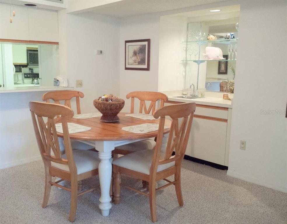 A dining area features a round wooden table with four chairs and a wet bar — 4449 46TH AVENUE W UNIT 4449, BRADENTON, FL