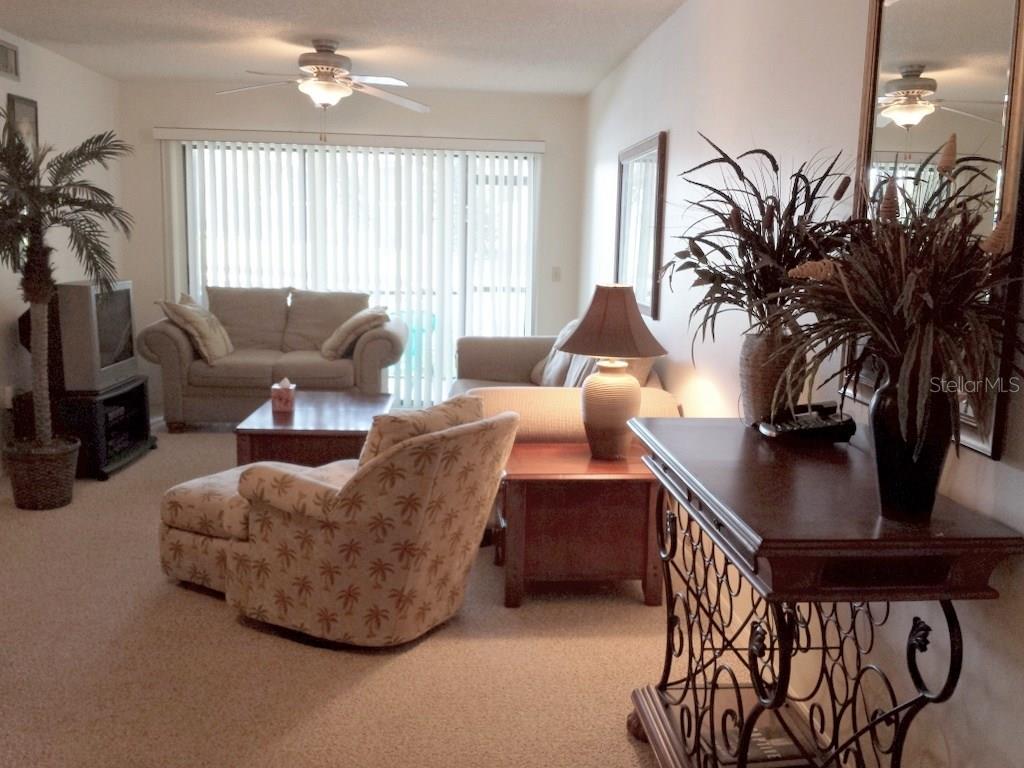 A living room featuring a patterned armchair, a sofa, a coffee table, and a console table — 4449 46TH AVENUE W UNIT 4449, BRADENTON, FL