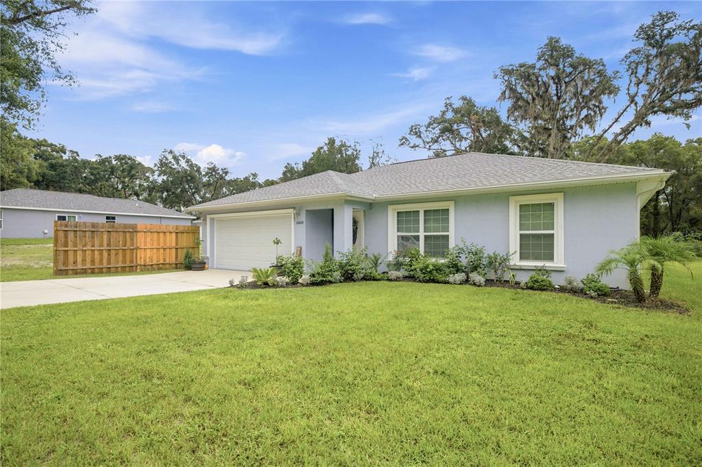 A light blue single-story house with a two-car garage and a large front lawn — 14825 SE 28TH TERRACE, SUMMERFIELD, FL