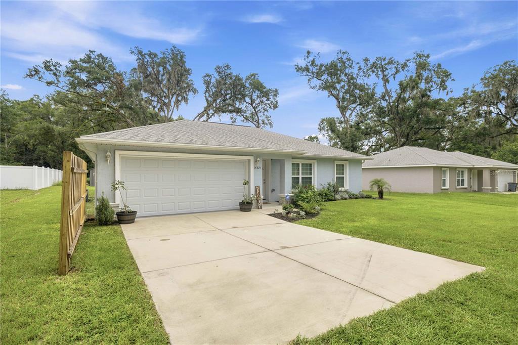 A light blue single-story house with a two-car garage and a concrete driveway — 14825 SE 28TH TERRACE, SUMMERFIELD, FL