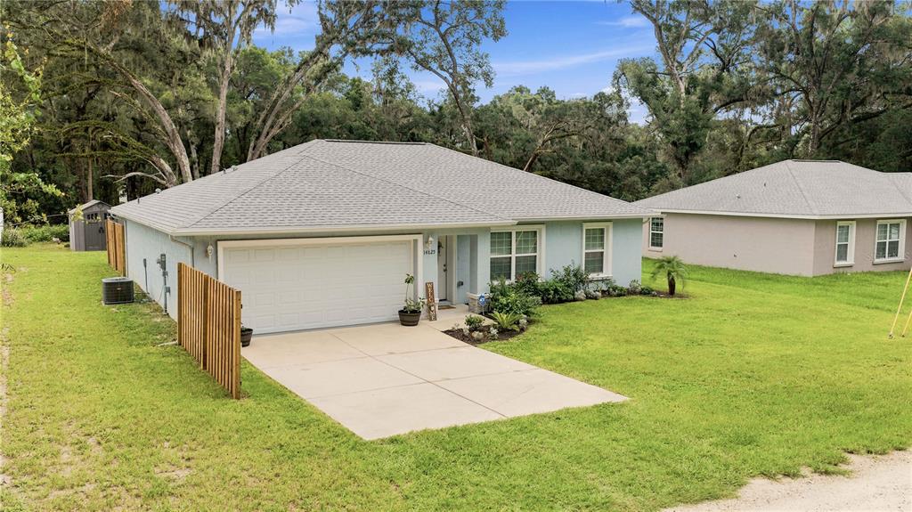 A single-story house with a light blue exterior, a gray shingled roof, and a concrete driveway — 14825 SE 28TH TERRACE, SUMMERFIELD, FL