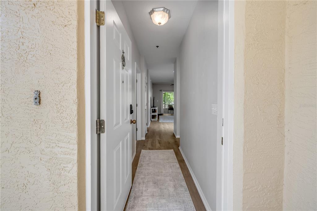 A view from an entryway looking down a hallway toward a living area with flooring — 132 TURNBULL VILLAS CIRCLE, NEW SMYRNA BEACH, FL