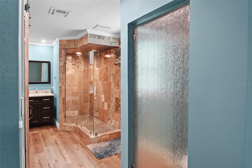 A backyard features a stone-clad house, a swimming pool with lounge chairs, and patio furniture — 9545 135TH STREET, SEMINOLE, FL