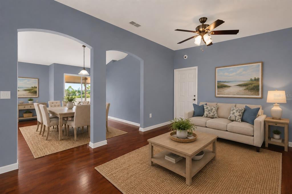 A living room and dining area feature blue walls, hardwood floors, and neutral furniture — 1147 NORMANDY DRIVE, KISSIMMEE, FL