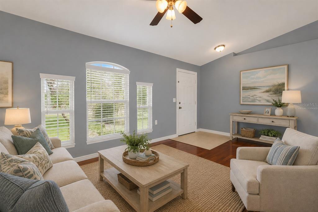 A living room features light blue walls, hardwood floors, a ceiling fan, and large windows — 1147 NORMANDY DRIVE, KISSIMMEE, FL