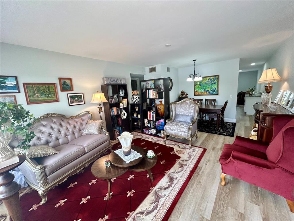 A living and dining area features a red area rug, traditional furniture, and wood flooring — 2286 NORWEGIAN DRIVE UNIT 8, CLEARWATER, FL