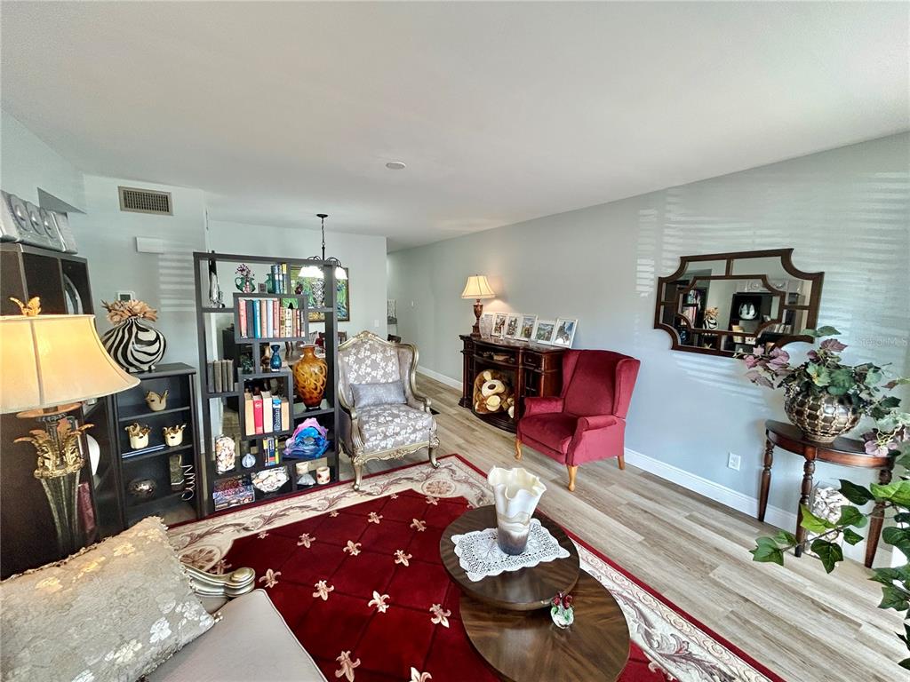 A living room features a red area rug, a room divider, and two accent chairs — 2286 NORWEGIAN DRIVE UNIT 8, CLEARWATER, FL