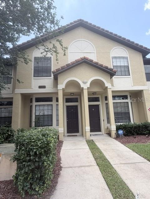 A two-story tan stucco building features two dark brown front doors under a shared portico — 6013 SCOTCHWOOD GLEN UNIT 17, ORLANDO, FL