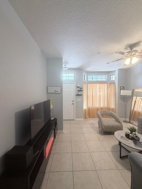 A living room features tile flooring, a television console with a fireplace, and bay windows — 6013 SCOTCHWOOD GLEN UNIT 17, ORLANDO, FL