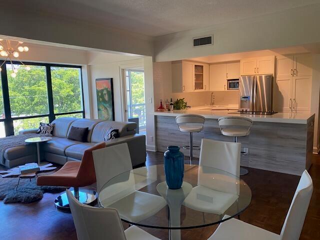 A living room with a sectional sofa, orange chair, and kitchen island with bar stools — 850 NE Spanish River Boulevard # 33, Boca Raton FL 33431, BOCA RATON, FL