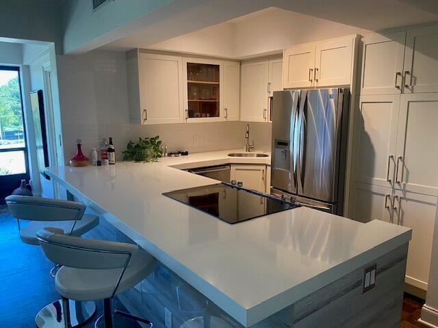 An open-concept living and dining area features a kitchen island, glass table, and sectional sofa — 850 NE Spanish River Boulevard # 33, Boca Raton FL 33431, BOCA RATON, FL