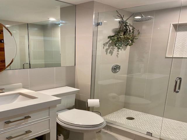 A kitchen features white cabinets, a stainless steel refrigerator, and a white countertop breakfast bar — 850 NE Spanish River Boulevard # 33, Boca Raton FL 33431, BOCA RATON, FL