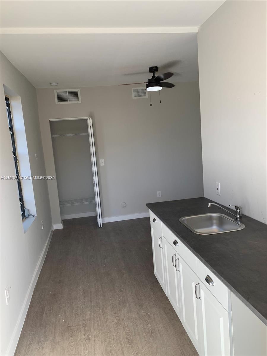 A small room features a kitchenette with white cabinets, a dark countertop, and a closet — 2932 NW 16th Ave # 3B, Miami FL 33142, MIAMI, FL
