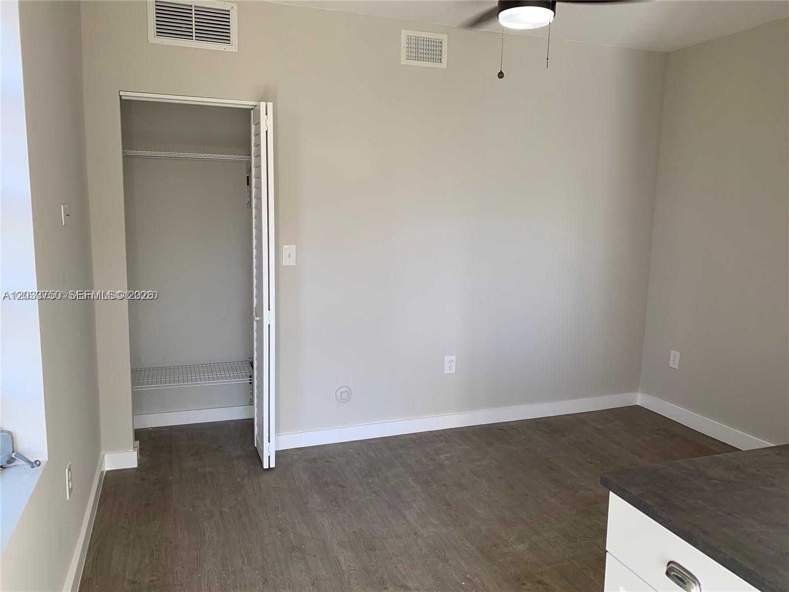 An empty room features light gray walls, wood-look flooring, a ceiling fan, and a closet — 2932 NW 16th Ave # 3B, Miami FL 33142, MIAMI, FL