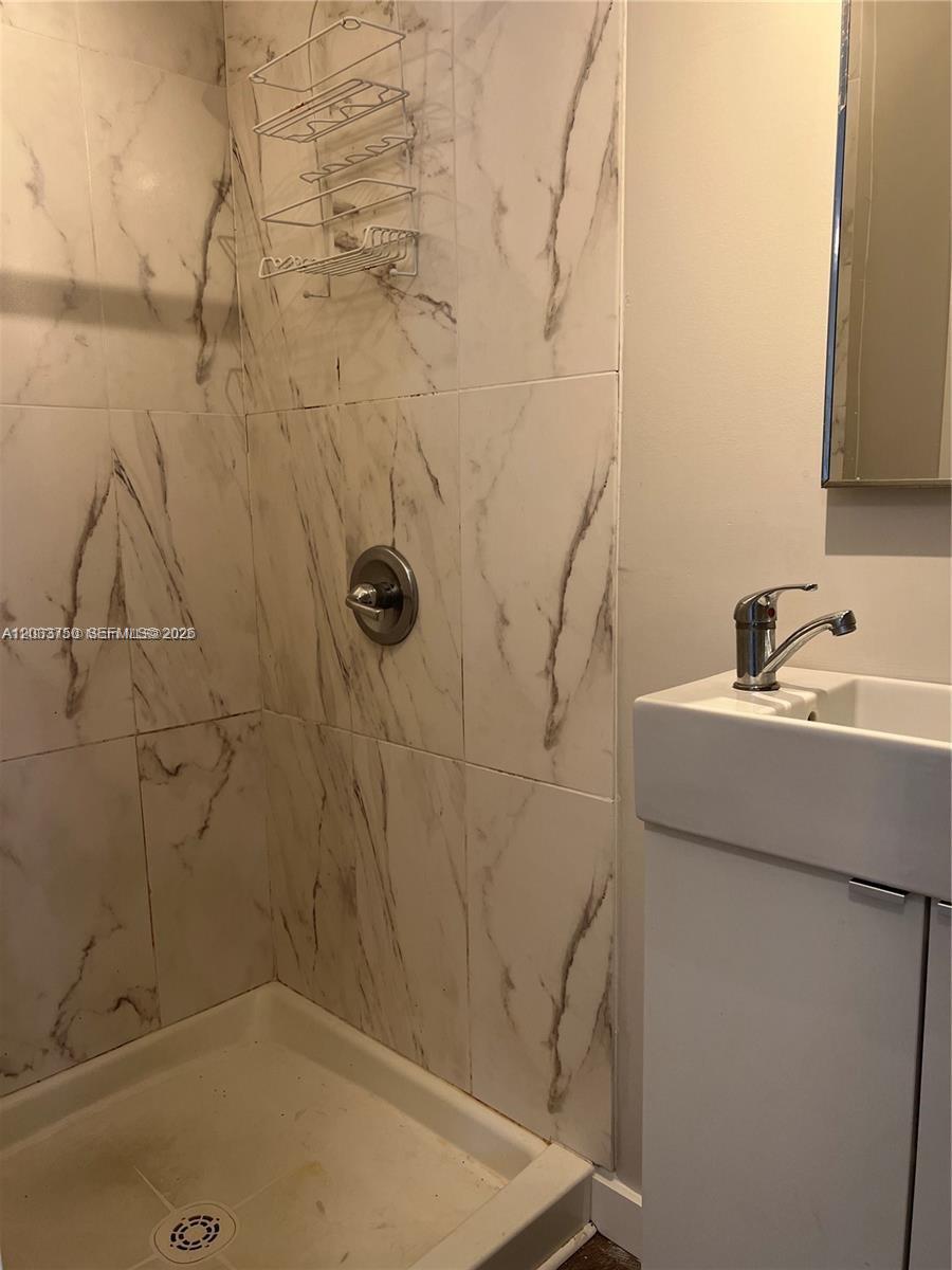 A bathroom features a walk-in shower with marble-patterned tile and a white pedestal sink — 2932 NW 16th Ave # 3B, Miami FL 33142, MIAMI, FL
