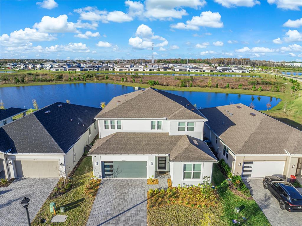 An aerial view of a two-story suburban house with a paved driveway and pond — 6920 ROSY SKY AVENUE, ORLANDO, FL