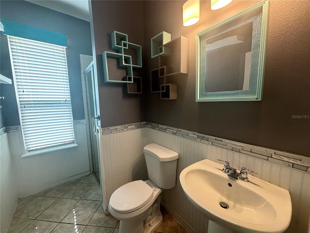A bathroom features a pedestal sink, a toilet, a shower stall, and wall-mounted cube shelves — 3795 MARIETTA WAY, ST CLOUD, FL