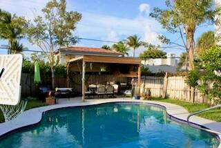 A backyard swimming pool with a wooden pergola covering a dining area and patio — 237 Wenonah Place, West Palm Beach FL 33405, WEST PALM BEACH, FL