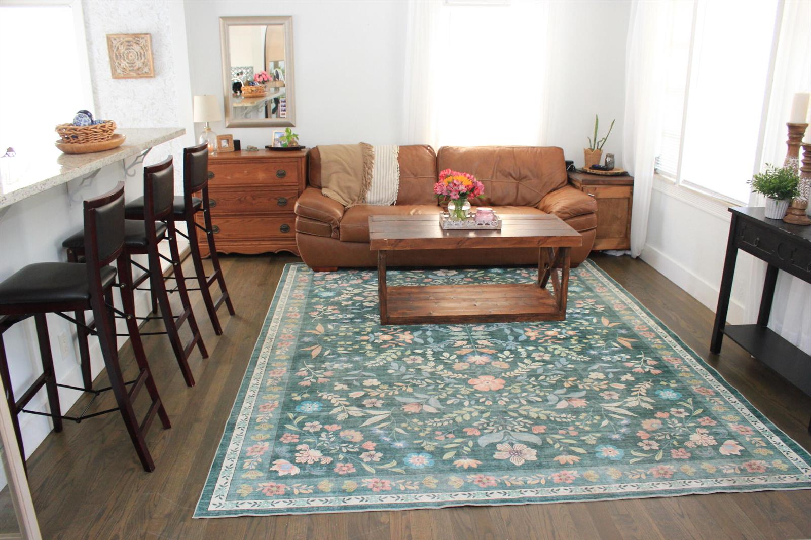 A living room with a brown leather sofa, floral area rug, and breakfast bar seating — 237 Wenonah Place, West Palm Beach FL 33405, WEST PALM BEACH, FL