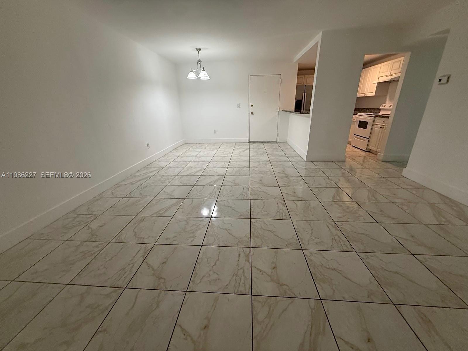 A dining area features white walls, a hanging light fixture, and light-colored marble-patterned tile flooring — 10393 N Kendall Dr # U7, Miami FL 33176, MIAMI, FL