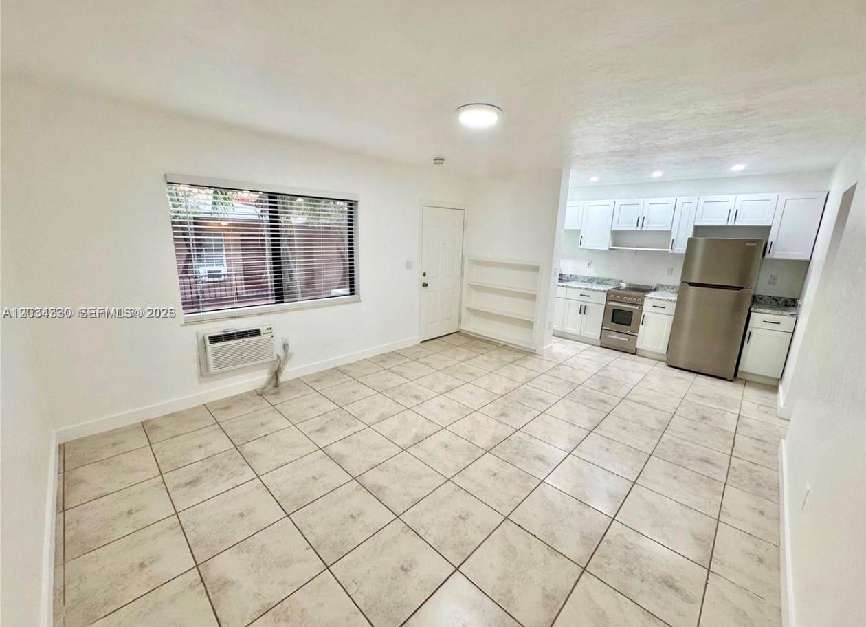 This room features white walls, tiled flooring, a window, and an open kitchen area — 550 SW 10th St # 6, Miami FL 33130, MIAMI, FL