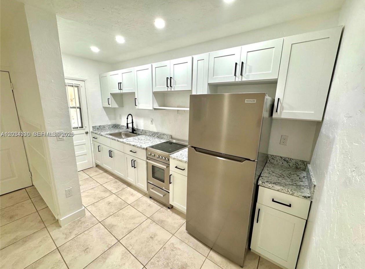 A kitchen features white cabinets, granite countertops, stainless steel appliances, and light tile flooring — 550 SW 10th St # 6, Miami FL 33130, MIAMI, FL