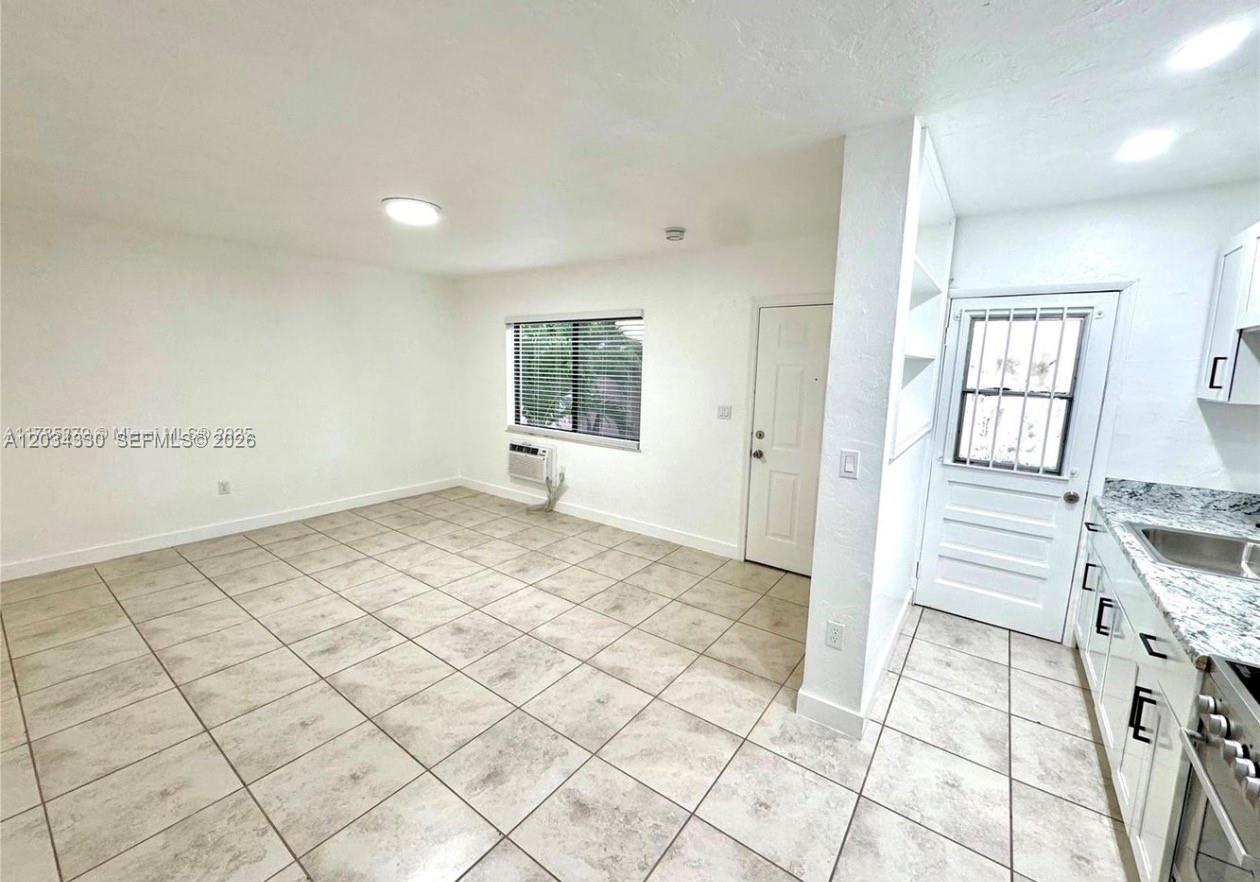 An interior view shows a kitchen with granite countertops adjacent to an open living area — 550 SW 10th St # 6, Miami FL 33130, MIAMI, FL