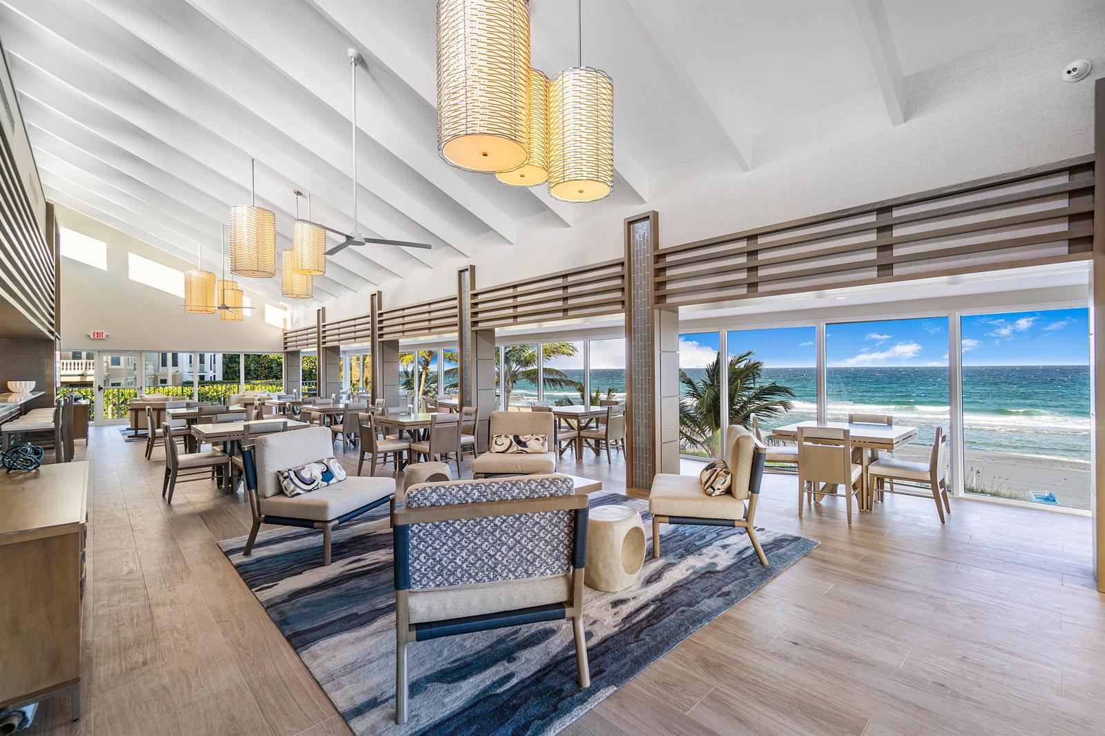 A bright, modern lounge area features ocean views, wood-look flooring, and several hanging pendant lights — 4740 S Ocean Boulevard S # 501, Highland Beach FL 33487, HIGHLAND BEACH, FL