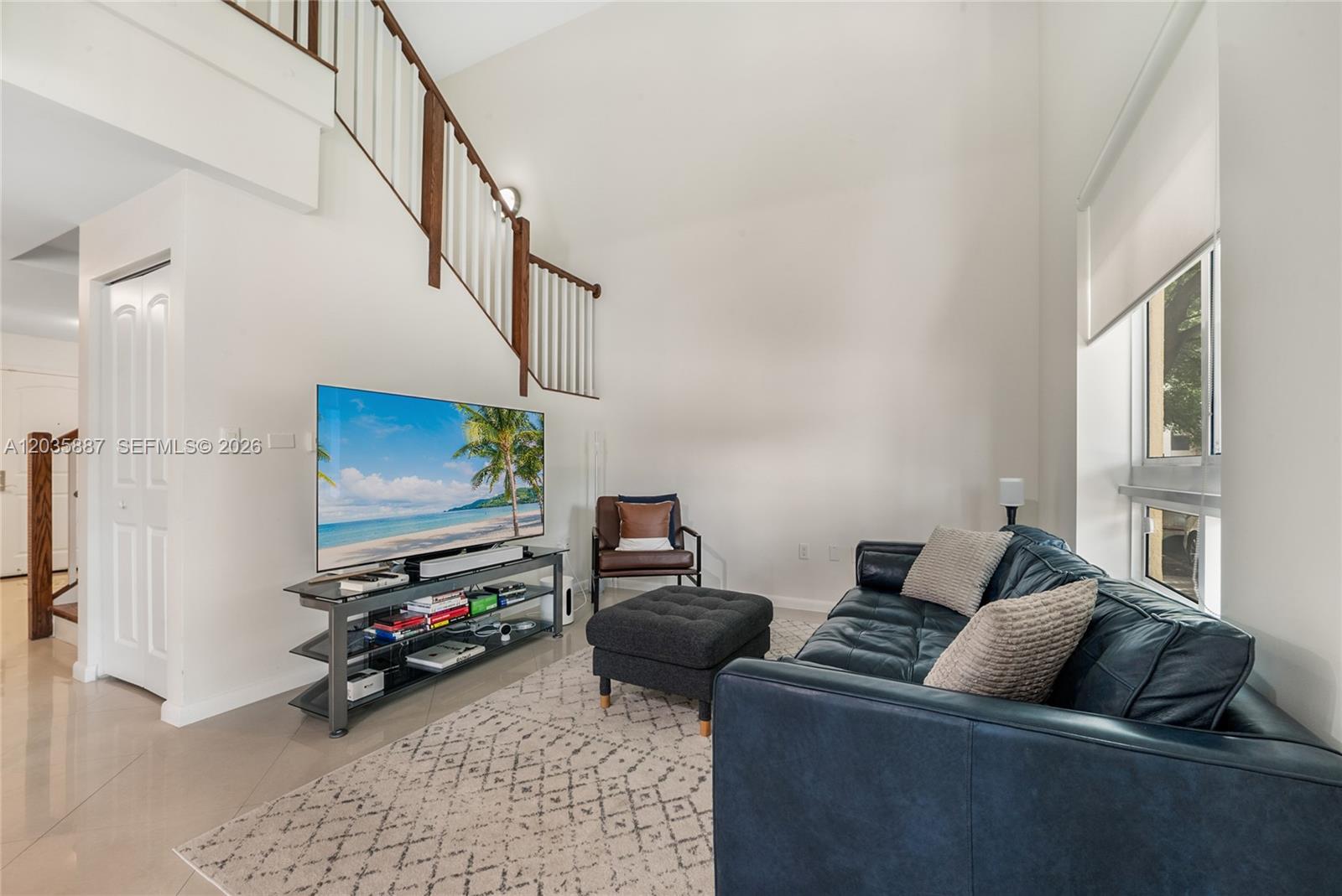 A living room features a dark leather sofa, a television on a stand, and stairs — 7375 SW 90th St, Miami FL 33156, MIAMI, FL