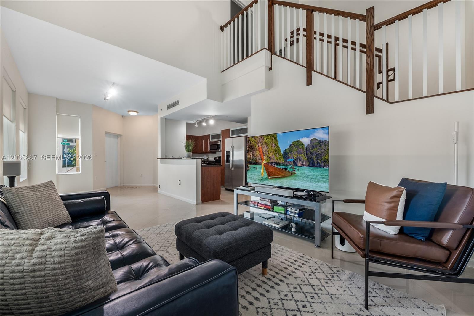 A living room features a black leather sofa, a dark ottoman, and a staircase — 7375 SW 90th St, Miami FL 33156, MIAMI, FL