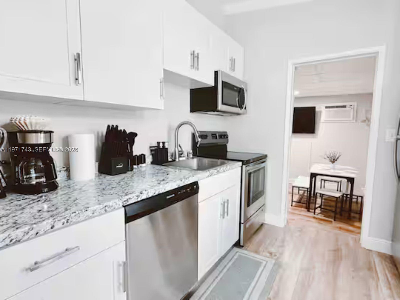 A kitchen features white cabinets, stainless steel appliances, and granite countertops — 308 NE 8th Ct # 0, Pompano Beach FL 33060, POMPANO BEACH, FL